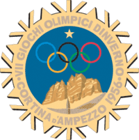 A stylized snowflake with the Olympic rings, a star and mountains. Surrounding the perimeter of the snow flake are the words, "VII Giochi Olimpici Dinverno, Cortina d'Ampezzo 1956"