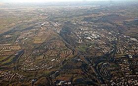 Cumbernauld from the air with St. Maurice's Pond at the bottom and Longannet Power Station on the far side of the Forth at the top. To the left the Forth and Clyde Canal and to the right Fannyside Lochs can be seen.