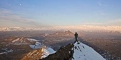 An ISAF member stands on top of a hill watching a snow-covered mountain range in Kabul province (March 1, 2013).
