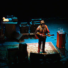 Photo of a man holding a guitar with a microphone nearby