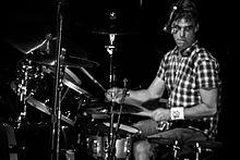 A male drummer, Matt Cameron, seated behind a drumkit of drums and cymbals.