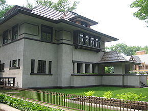 Recent exterior view of the house from the southeast corner. The library windows are visible at left with the entrance porch at far right. The living room planter with bedroom bay window are at center. Deep eaves shade the house from the mid-day summer sun.