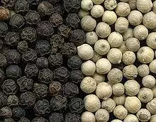 Black peppercorns on the left and white peppercorns on the right