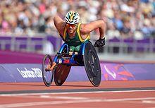 A photo of Kurt Fearnley, in a wheelchair, racing on a track