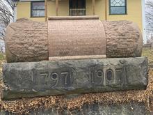 This image shows a monument in the shape of a scroll dedicated to the founder of Meadville, David Mead
