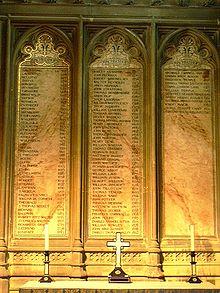 Three plaques on a wall, inscribed with the lists of the archbishops. In front of the plaques is a table with two candlesticks flanking an upright cross.