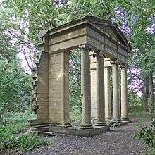 An arch with columns and a pediment standing alone in a woodland