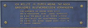 A plaque with the German text in all capital letters:'"Ich wollte ja durch meine Tat noch größeres Blutvergießen verhindern." Zum Gedenken an Johann Georg Elser, der in Königsbronn seine Jugend verbrachte. Am 8. Nov. 1939 wollte er mit seinem Attentat auf Adolf Hitler das Völkermorden verhindern. Am 9. April 1945 wurde Johan Georg Elser im KZ Dachau ermordet.'