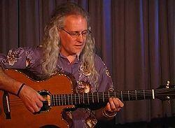 Tony Cox performing at the Grahamstown National Arts Festival, South Africa, in June 2005. He is pictured playing a long scale length acoustic baritone guitar custom made for him by Ian Corr.