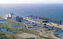 An industrial seaport sits on the coast of a large body of water