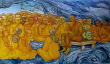 Mural painting with many monks sitting in a cave, one of them seated on a bench