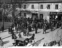 A large number of people crowd outside a building.