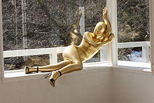 Woman in gold zentai and black heels posing on a windowsill