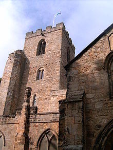 A stone church building with a tower. A Saltire flag flies on a pole on the top of the tower.