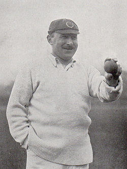 A black and white photograph of a cricketer holding a cricket ball