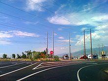 A two lane road with a separate turning lane, with a red octagonal stop sign in the middle.