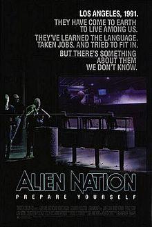 A black poster. Above in bold letters are the lines: "Los Angeles, 1991." "They have come to earth to live among us." "They've learned the language." "Taken jobs." "And tried to fit in." "But there's something about them we don't know." Below, in large typeface is the line: "Alien Nation" and in smaller typeface, the line: "Prepare Yourself," with the film credits underneath. In the background are three extraterrestrials standing on a street corner. One of the figures is a female standing next to a waste basket and three newspaper stands, holding a jacket over her shoulders. Behind her is a bar that features alien typography on its walls. Two extraterrestrials who are hanging out inside the bar, can be seen through its glass window.