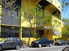 Yellow, multi-story building with cars parked in front
