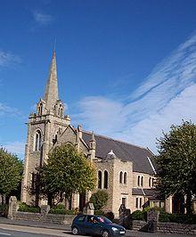 A stone building consisting of a three-storey central body with pitched roof. At one corner of the building is a tower with an Octagonal spire.