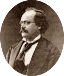 photograph of middle-aged white man with receding dark hair, spectacles and moustache, in semi-profile, facing right