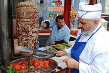 A cook slices ingredients into a skillet