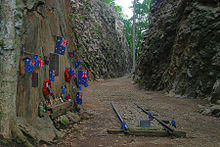 Abandoned railway lines in a deep rocky cutting adorned with memorial flowers