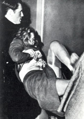 Woman being restrained by police officer, her legs kicked in front of her