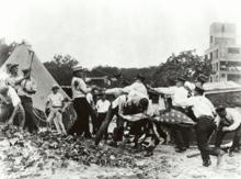 Police with batons confront demonstrators armed with bricks and clubs. A policeman and a demonstrator wrestle over a U.S. flag.
