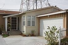 A bungalow with an attached garage with a tower and power lines in the background