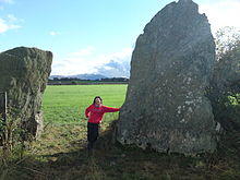 Bryn Gwyn stones, small adult leaning on slab stone, 11102009.JPG