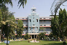 Three-story building with central column, framed with palm trees