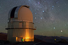 Picture of an large telescope dome against a night sky showing Alpha and Beta Centauri, the constellation Crux, and other stars as well as the Milky Way