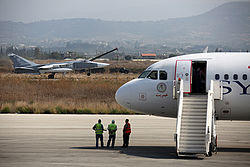 Russian Air Force Sukhoi Su-24 passes a Syrianair Airbus A320 at Latakia.jpg