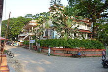 Large, older building surrounded by trees and shrubs