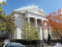 A white Neoclassical religious building in a residential neighborhood
