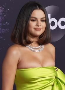 Gomez stands in a lime green dress against a purple backdrop