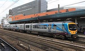 A three-car train in grey and light blue colours at a station