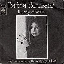 In this black-and-white photograph, Barbra Streisand appears wearing a shawl around her head with her hand against a wall.