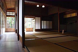 View along wood-floored engawa towards a corner showing shōji edge-on and, on the far side of the corner, from the inside, with light shining through.