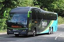 Photograph of the South West Falcon coach, in distinctive yellow, blue and green colours, seen driving along the A38