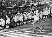Athlete running down steps holding the Olympic torch