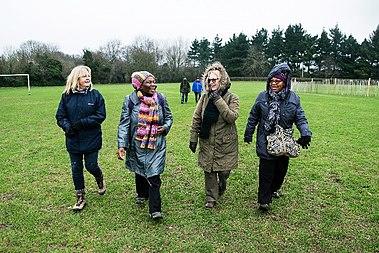 Four people on a walk, crossing a grassy area
