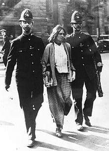 A woman under arrrest walking between two policemen