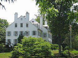 Side view of a white, masonry two-and-a-half story house