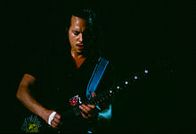 Long–haired guitarist soloing on a colored guitar